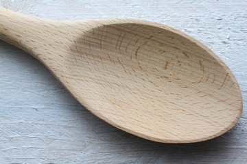 Wooden kitchen trowel on shabby looking white table closeup