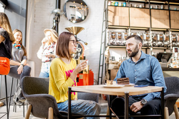 Couple of friends dressed casually having a conversation during the coffee break in the beautiful cafe
