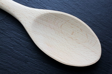 Wooden kitchen trowel on slate board closeup