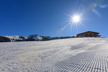 frisch präparierte Skipiste in den Alpen bei Sonnenschein