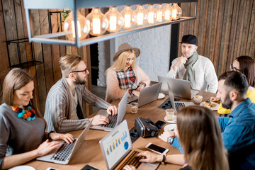Young coworkers dressed casually sitting with laptops during the conference in the modern loft workspace