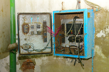 Old dismantled and rusty electrical panel assembly on an abandoned and destroyed factory against a...