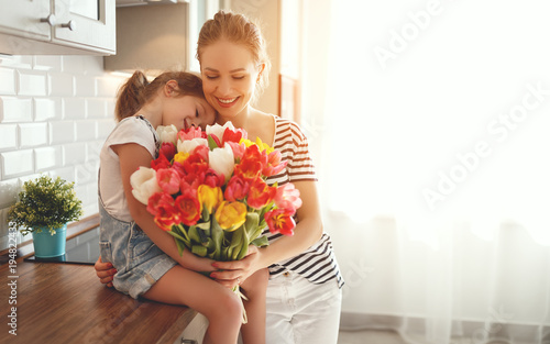 happy mother's day! child daughter   gives mother a bouquet of flowers to tulips