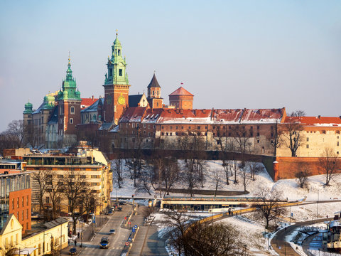 Krakow, Poland. Wawel Cathedral and castle in winter with snow, Vistula river bank and hotels. Aerioal view in sunset light.