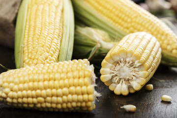 Fresh corn on cobs on rustic wooden table, closeup