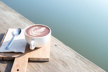 White coffee cup art with spoon, tissue, chopping board on wooden table in coffee shop. vintage style effect picture, with copy space