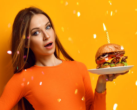 Woman Hands Hold Big Burger Barbeque Sandwich With Beef And Lit Candle For Birthday Party On Yellow