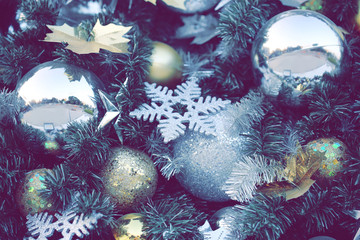 gold color Christmas ball hang on green pine tree with blurred night light new year party background.