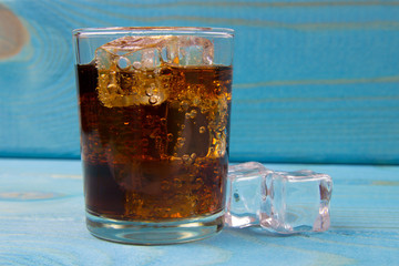 Sweet, fizzy drink with ice on a blue background.