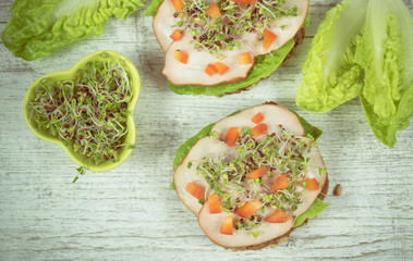 Sandwiches with lettuce, ham and broccoli sprouts.