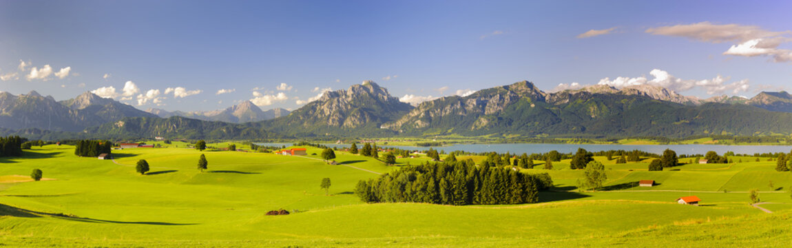 panoramic landscape in region Allgaeu with lake and alps mountain range