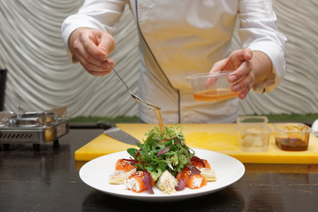 Chef is pouring sauce on appetizer