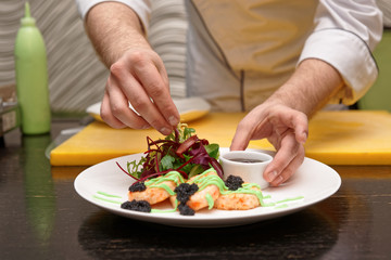 Chef is serving crab cakes with salad mix, gravy, seaweed caviar and wasabi