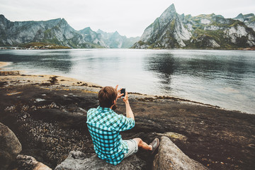 Man tourist taking selfie by smartphone sightseeing Lofoten islands rocks Travel lifestyle...