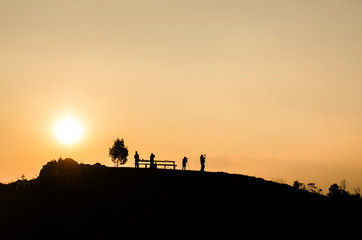 Fototapeta na wymiar silhouette of people on the top of mountain with sun set background