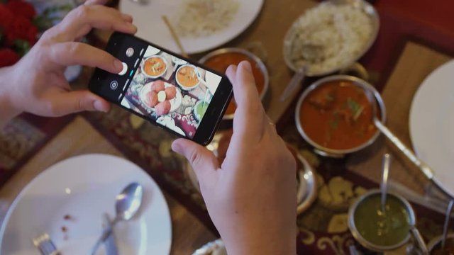 Close up of hands with smartphone taking a pic of indian food for social network site. 3840x2160