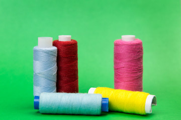 Threads of different colors on a green background. A few coils with bright multicolored threads stand on a juicy green background.