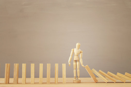 A wooden dummy stopping the domino effect. retro style image executive and risk control concept.