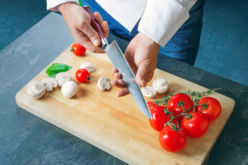 Professional chef cuts vegetables with a sharp knife from Damascus steel.