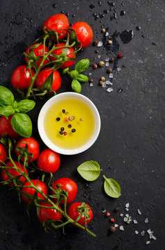 Italian food ingredients – tomatoes, basil and olive oil on black background, top view, flat lay.