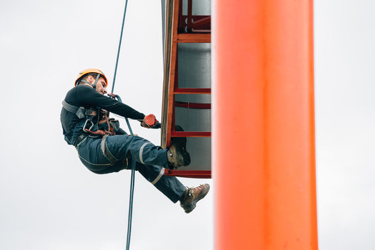 Industrial climber hangs a poster on a billboard