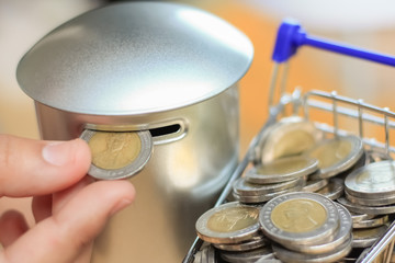 Hand picking coins from a Shopping cart into a coin bank, Saving money concept.