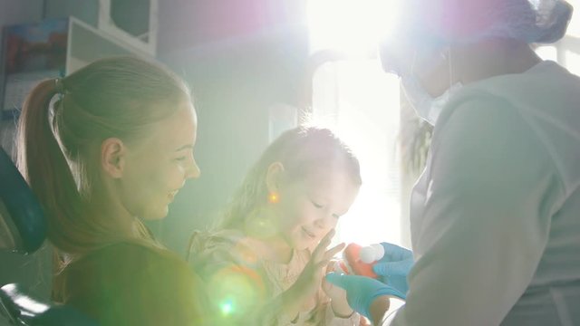 Young woman, her daughter and dentist in a dental office, a stomatologist telling how to care for teeth