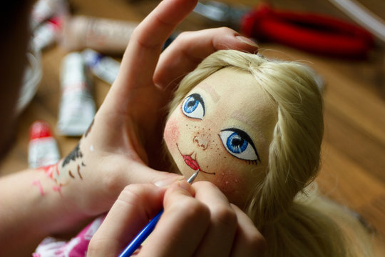 Hand sewing doll toy, facial painting, homework, leisure and hobby.