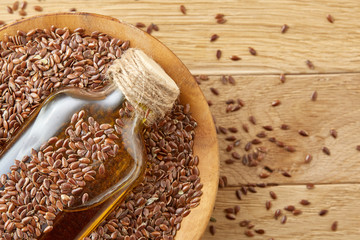 Top view closeup picture flax seeds and linseed oil in a glass bottle on a wooden background, shallow depth of field.