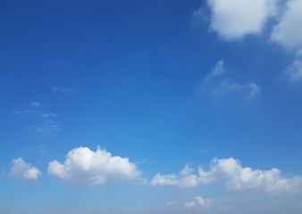 Clear sky with white puffy clouds and shades and hues of different blue with copy space