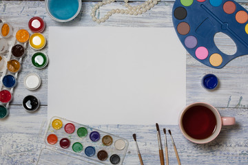 Mock up. Creative space. Artist workspace on vintage wooden table: watercolor, white paper, paint...