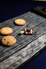Chip-cookies  and peanuts on a dark old wooden tray on blue background.