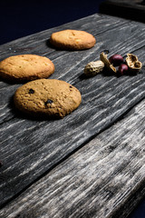 Chip-cookies  and peanuts on a dark old wooden tray on blue background.