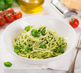 spaghetti pasta with basil pesto sauce and parmesan cheese on white bowl