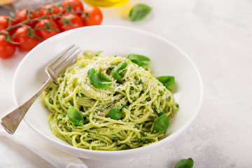 spaghetti pasta with basil pesto sauce and parmesan cheese on white bowl
