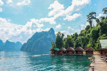Wooden Thai traditional long-tail boat on a lake with mountains and rain forest in the background during a sunny day at Ratchaprapha Dam at Khao Sok National Park, Surat Thani Province, Thailand