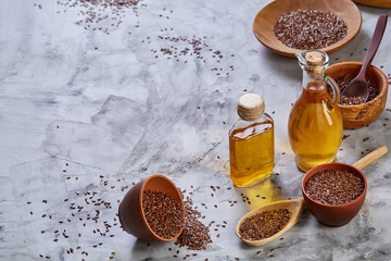 Flax seeds in bowl and flaxseed oil in glass bottle on light textured background, top view,...