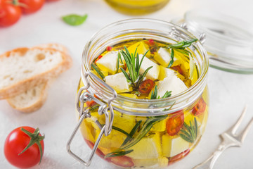 marinated feta cheese with olive oil, spicy herbs, garlic and chili pepper in jar, selective focus