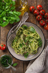 spaghetti pasta with basil pesto sauce, parmesan cheese and microgreens, wooden background, top view,