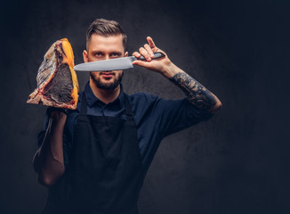 Professional butcher holds a knife and big piece raw smoked meat