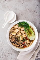 asian vegan noodle soup with tofu cheese,shiitake mushroms and pak choi in white bow