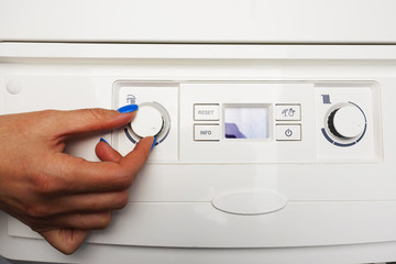 Woman hand adjusting the temperature of the gas central heating 

