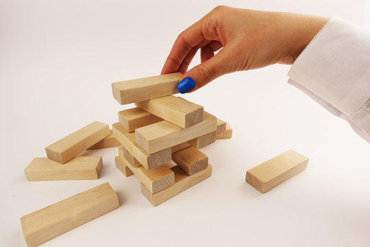 Risk assumption concept, business strategy with woman hand placing wooden pieces on a tower

