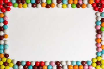 Round chocolate Bonbons covered with colored glaze on white background. Top view. Copy space.