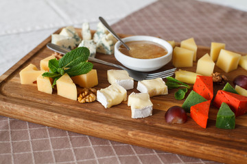 Cheese plates served with grapes, jam and nuts. Wooden desk