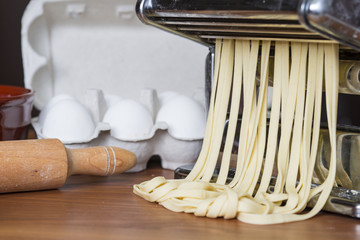 Fototapeta na wymiar machine for rolling dough and cutting Italian pasta, eggs and flour