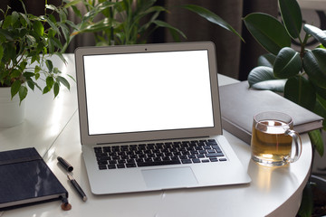  Laptop on white table on background of green plants