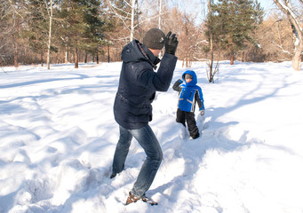 father and son playing snowballs in the forest