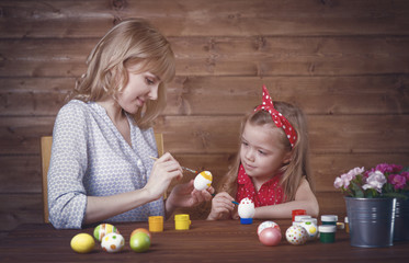 Naklejka premium Mom and daughter paint Easter eggs