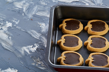 Fresh baked chocolate apple shaped cookies on a cookie sheet, top view, close-up, selective focus